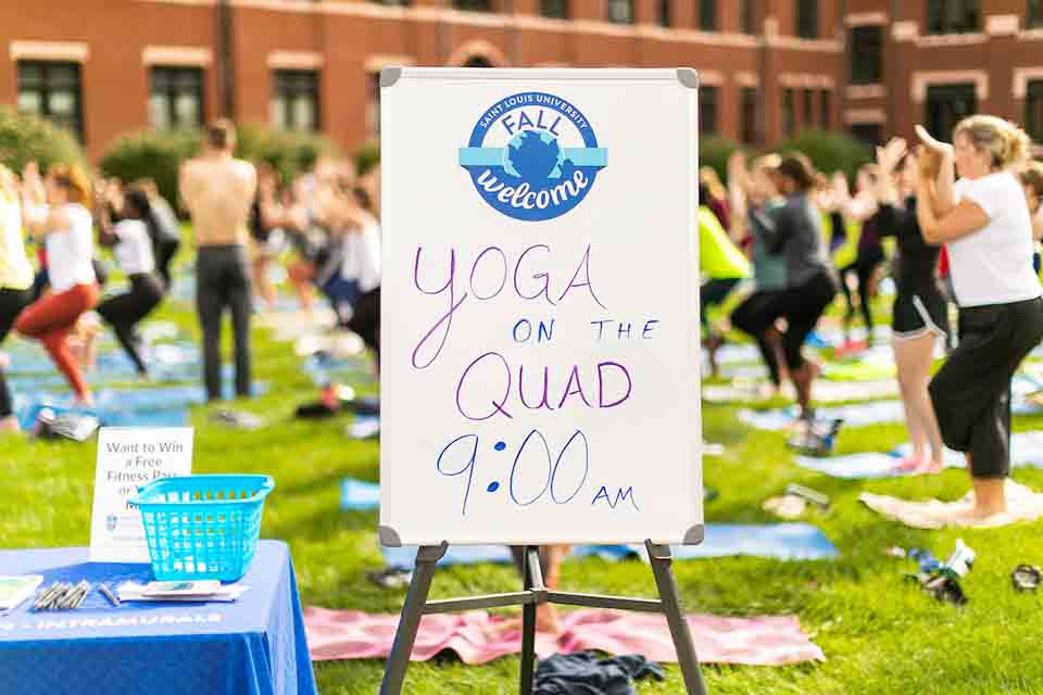 背景是练习瑜伽的人们，前景是写着"上午9点在四方广场瑜伽"的标语。
